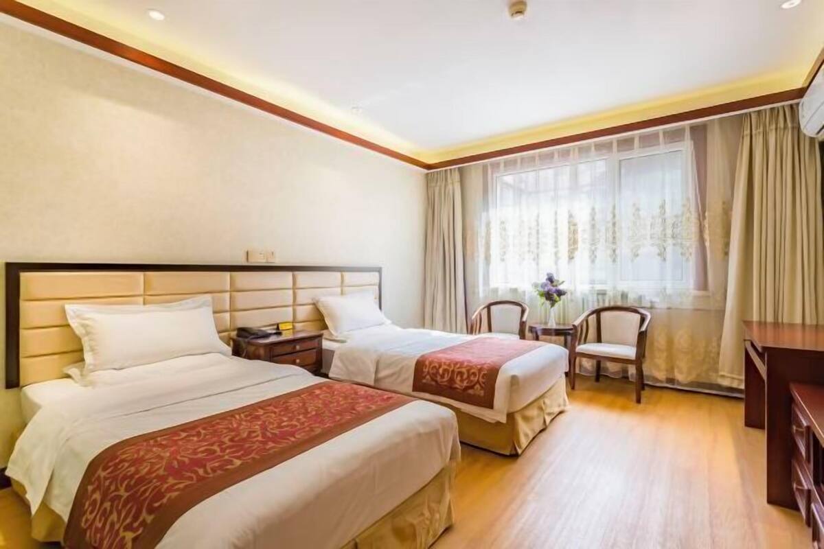 A hotel room with two beds, a desk, and a chair.