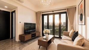 A modern living room with a television, sofa, coffee table, and a view of the city.