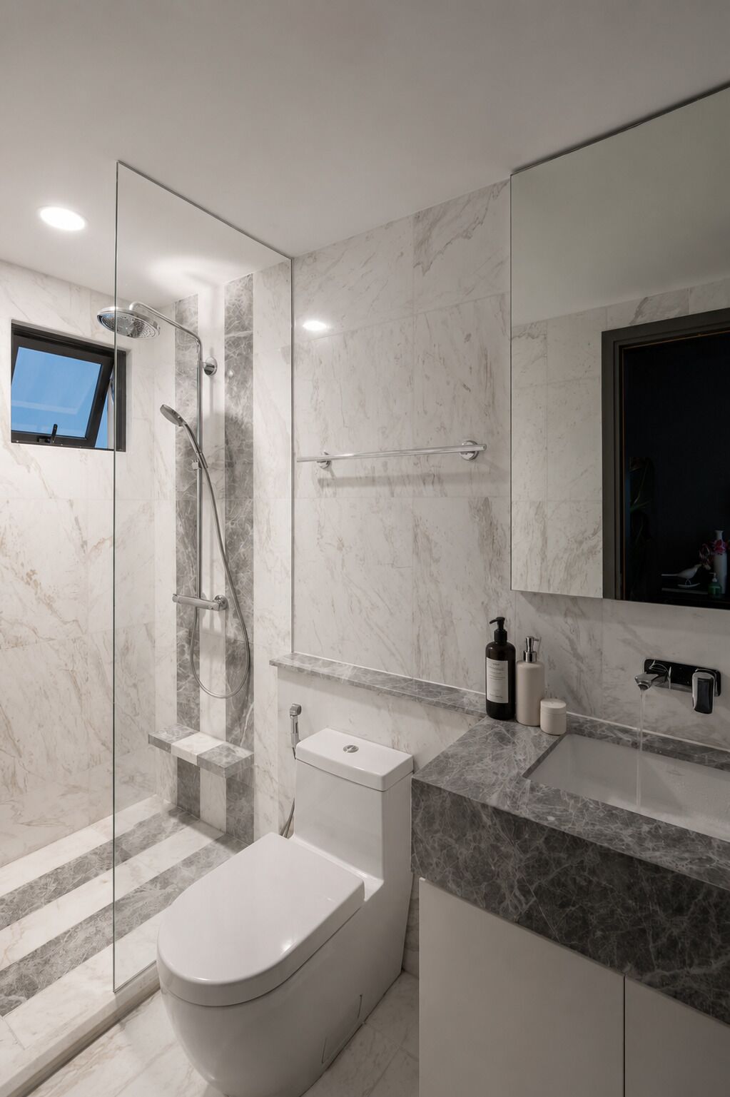 Een moderne badkamer met een glazen douchecabine, toilet en wastafel met spiegel.