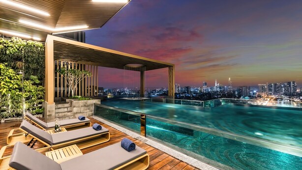 A rooftop infinity pool with lounge chairs and a cityscape view at sunset.