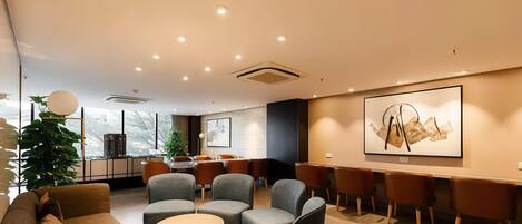A modern lounge area with comfortable seating, a bar, and a large abstract painting on the wall.