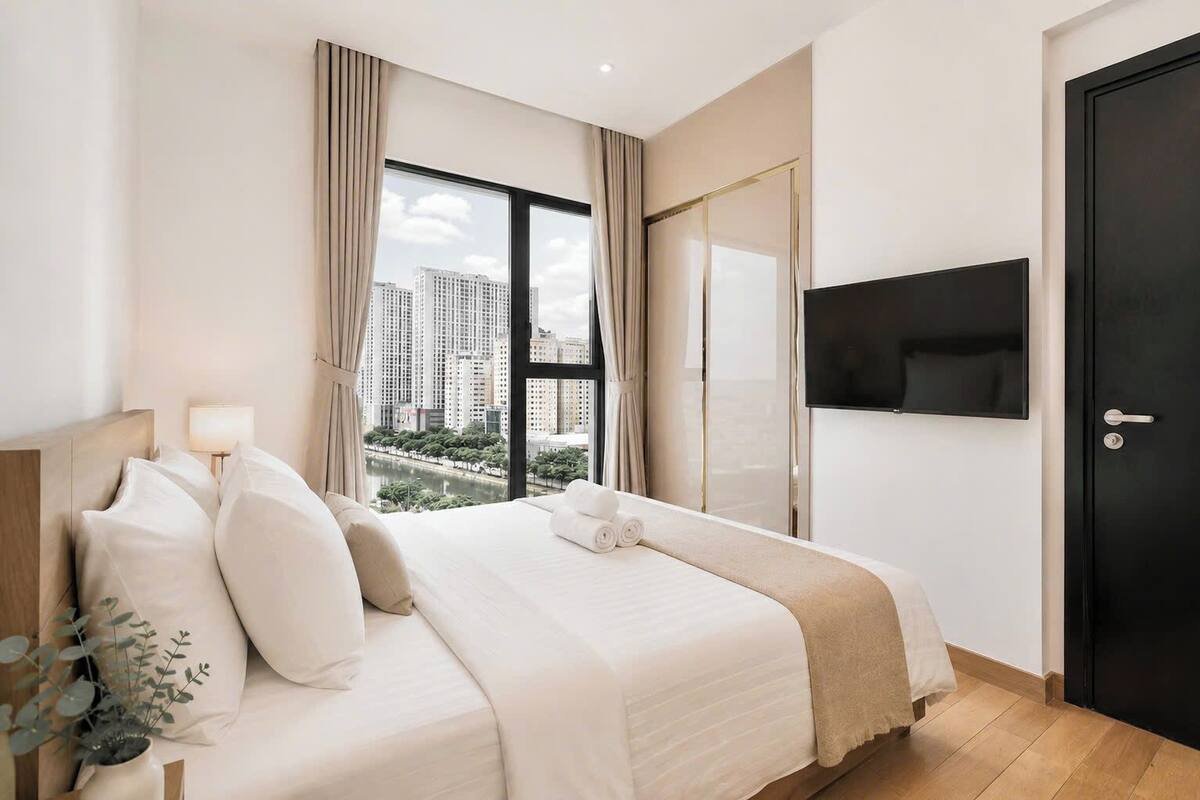 Ein Hotelzimmer mit Bett, Fernseher, Fenster mit Vorhängen und einer Tür.