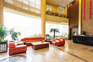Eine geräumige Lobby mit hoher Decke, einem Empfangsbereich und einer Sitzecke mit Sofas und einem Couchtisch.