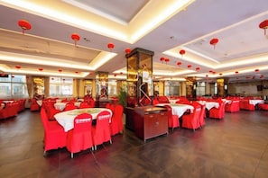 Ein geräumiges Restaurant mit mehreren Tischen und Stühlen, roten Laternen und einer zentralen Zierensäule.