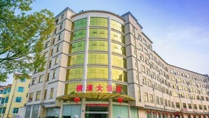 Ein Hotel mit einer geschwungenen Fassade, großen Fenstern und einem markanten Eingang mit roten Laternen.