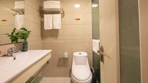 A small bathroom with a sink, toilet, and a mirror. There are towels on a rack and a plant on the counter. - Hengdian World Studios Hengpiao Grand Hotel (Dongyang)
