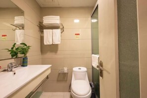 A small bathroom with a sink, toilet, and a mirror. There are towels on a rack and a plant on the counter. - Hengdian World Studios Hengpiao Grand Hotel (Dongyang)