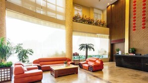 Eine großzügige Lobby mit hoher Decke, einer Rezeption und Sitzbereichen.