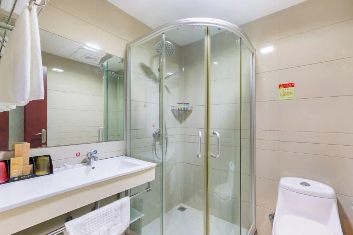A modern bathroom with a glass-enclosed shower, a white sink, and a toilet.