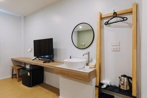 A modern bathroom with a wooden vanity, a round mirror, a sink, and a black television on a stand. - Chotana Bed (Chiang Mai)