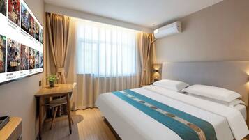 A hotel room with a bed, a desk, a chair, a window with curtains, and wall-mounted air conditioning.