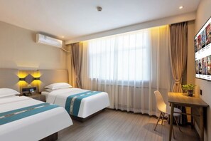 Une chambre d’hôtel avec deux lits, un bureau, une chaise et une grande fenêtre avec des rideaux.