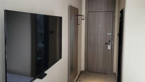 Een hal met een flatscreen televisie aan de muur, een deur met een hendel en een lamp aan het plafond.