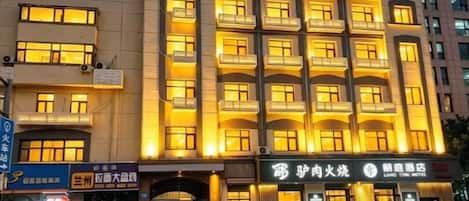 A multi-story hotel with balconies, a ground-level entrance, and signage for a restaurant and a hotel.