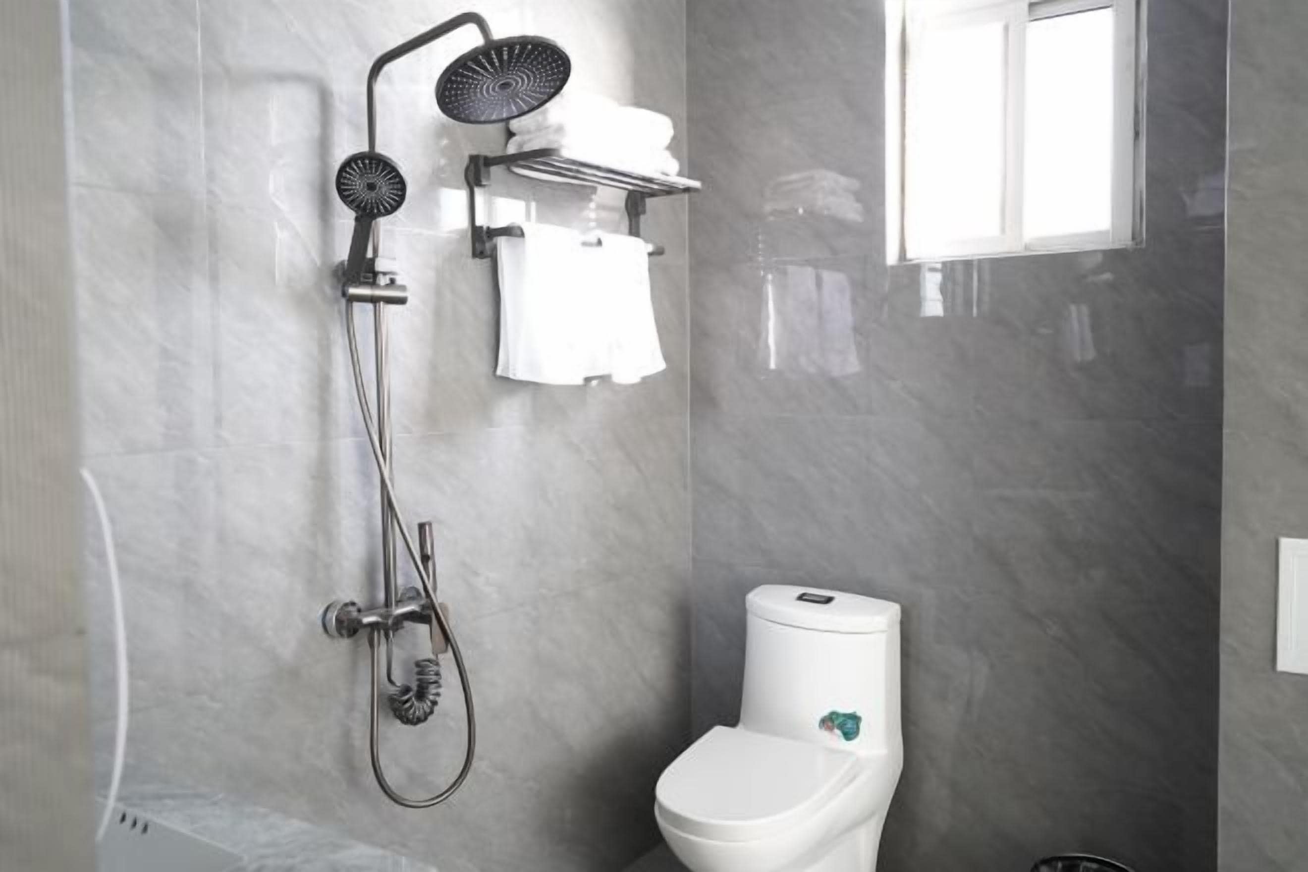 A bathroom with a shower, toilet, and towel rack.