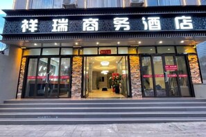 A hotel entrance with a signboard, glass doors, and a staircase leading up to the entrance.