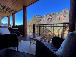 A wooden deck with wicker furniture, a stone vase, and a view of red rock mountains. - Stunning Views! Oak Creek Canyon's Zen Hideaway (Sedona)