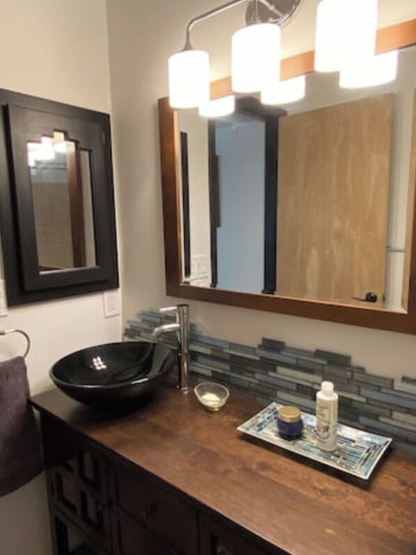 A bathroom with a black vessel sink, a mirror with a wooden frame, and a magazine on the counter. - Stunning Views! Oak Creek Canyon's Zen Hideaway (Sedona)
