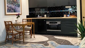 Eine moderne Küche mit schwarzen Schränken, einem Holztisch und einem Fliesenboden.