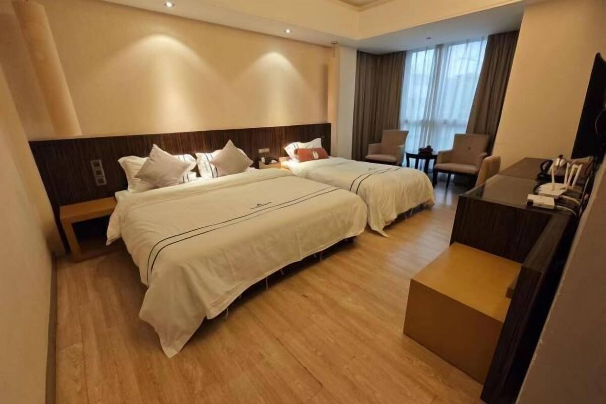 Ein Hotelzimmer mit zwei Betten, einem Schreibtisch und einem Sessel.