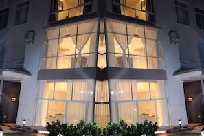 Um hotel com fachada em esquina, janelas amplas e entrada bem iluminada.