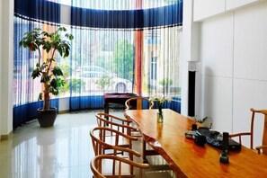 A dining area with a wooden table, chairs, a potted plant, and a window with curtains. - Jinse Gangwan sea veiw Villa (Dongshan County)