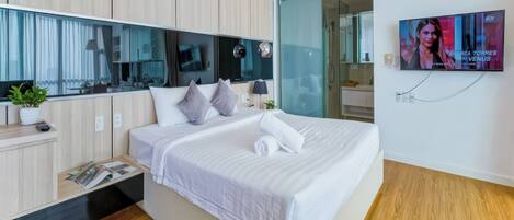 Une chambre d’hôtel moderne avec un grand lit, un téléviseur fixé au mur et un plancher en bois.