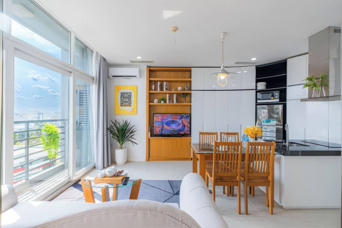 A modern kitchen with a dining area, large windows, and a view of the city.