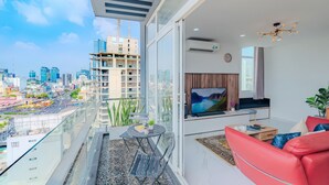 A modern apartment with a balcony, city view, and a living area with a TV, sofa, and coffee table. - Ben Thanh Tower - Luminous Apartments D1 (Ho Chi Minh City)