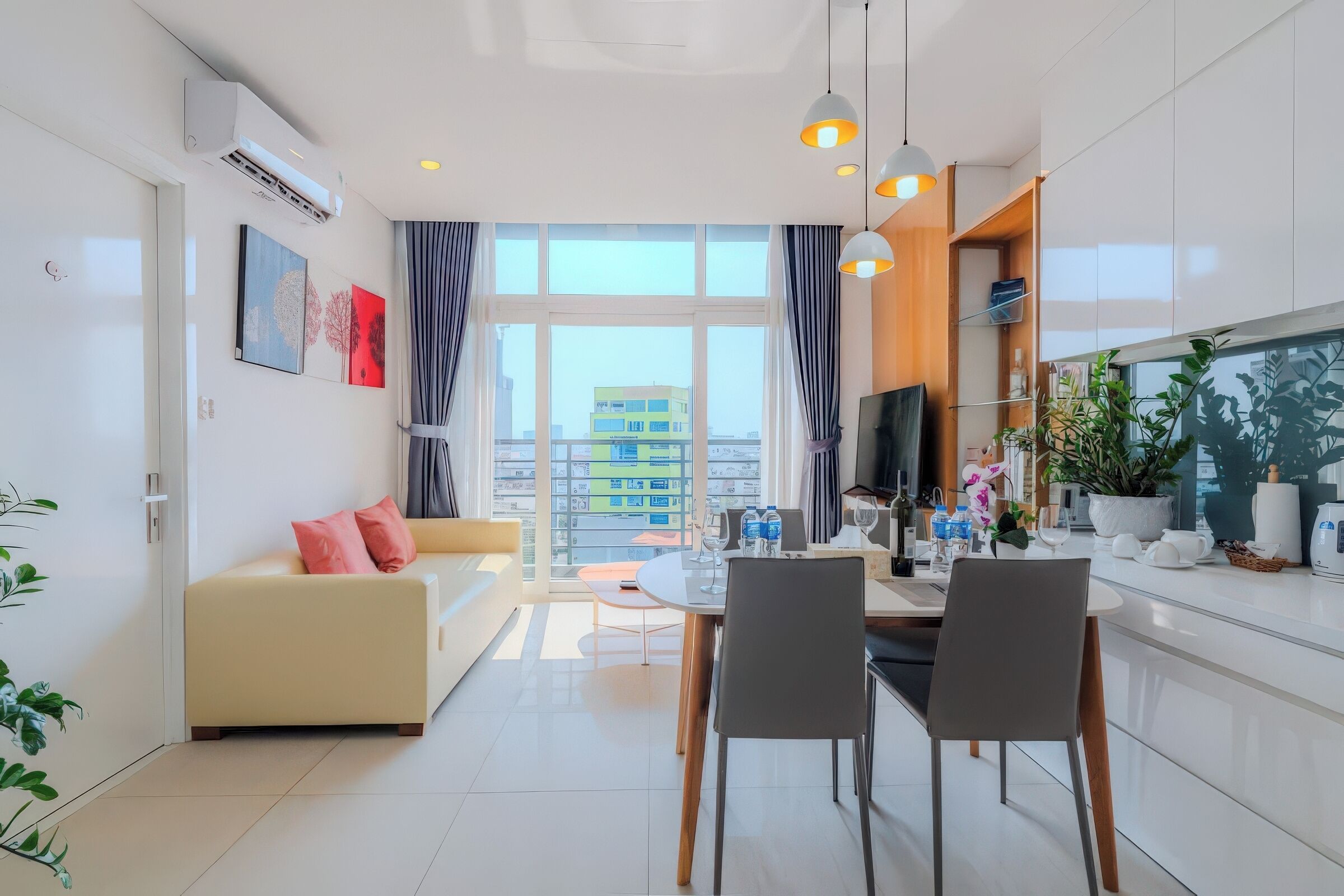 A modern living room with a sofa, dining table, and chairs, a TV, and a large window with curtains.