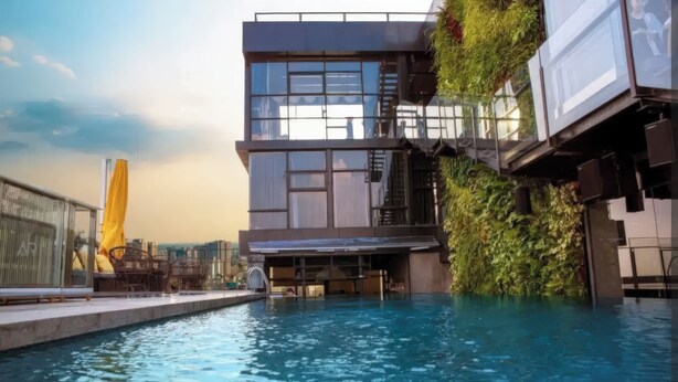 A modern building with a rooftop pool, glass windows, and a green wall. - Ben Thanh Tower - Luminous Apartments D1 (Ho Chi Minh City)