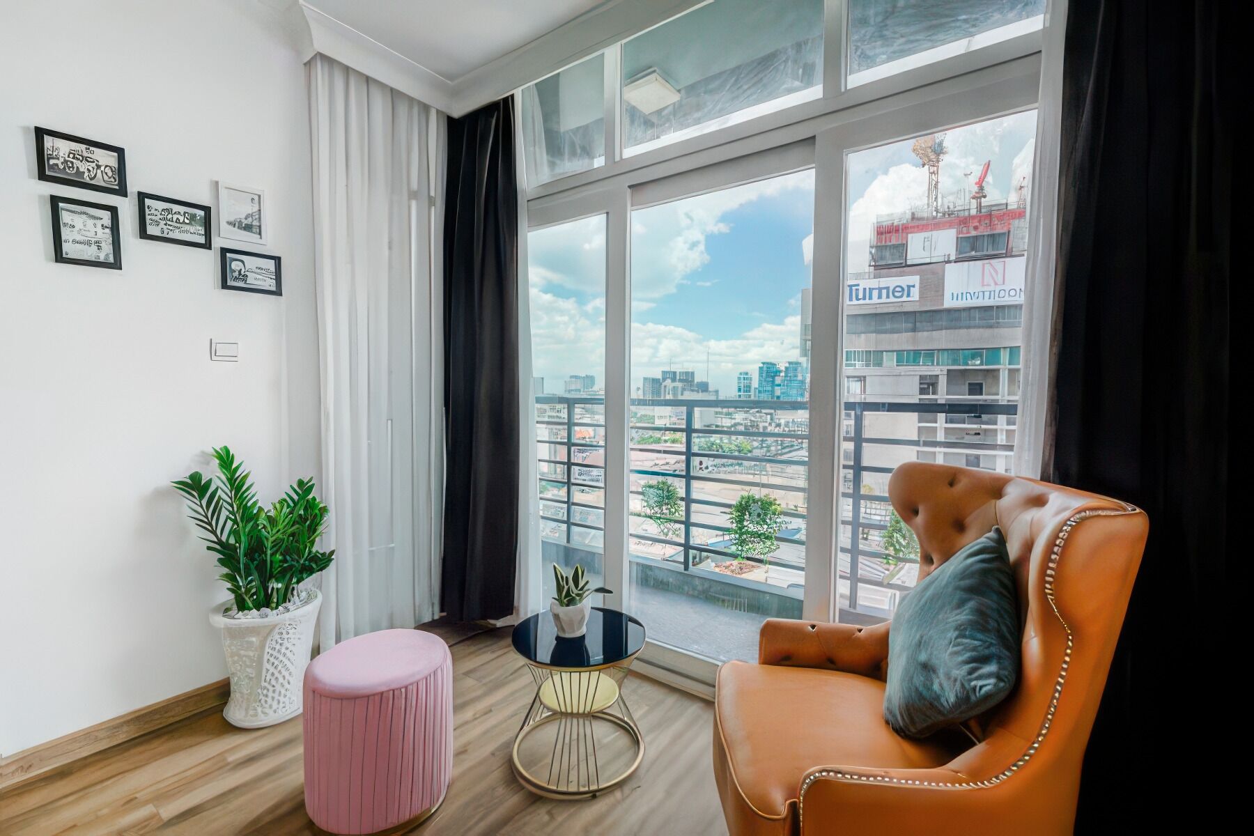 A modern living room with a large window, a leather armchair, a small round table, and a potted plant.