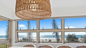 A dining area with a view of the beach and ocean through large windows. - Surfsong on Miami Beach (Miami)