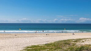 A beach with people, a lifeguard tower, and a flag. - Surfsong on Miami Beach (Miami)