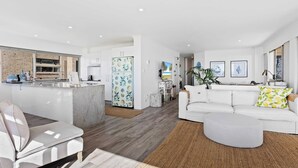 A modern living space with a kitchen, dining area, and a white sofa with a round ottoman. - Surfsong on Miami Beach (Miami)