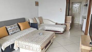 Una habitación con sofá, cama, televisor y una mesita.