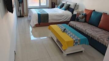 Una habitación de hotel con una cama, un sofá, una mesita y un ventilador.