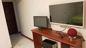 Een kamer met een houten bureau, een computer monitor, een desktop computer en een televisie.