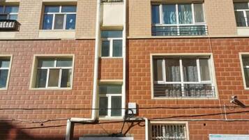 A multi-story building with a brick facade, multiple windows, and a visible air conditioning unit.