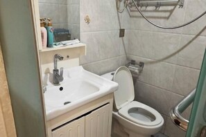 Een badkamer met een wastafel, toilet en douchehoek.
