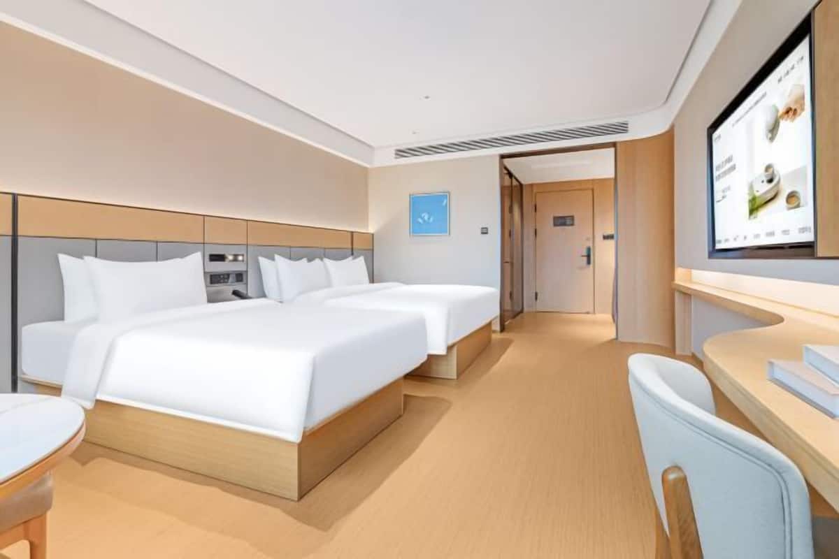 Ein modernes Hotelzimmer mit einem großen Bett, Nachttischen, einem Schreibtisch und einem Fernseher.