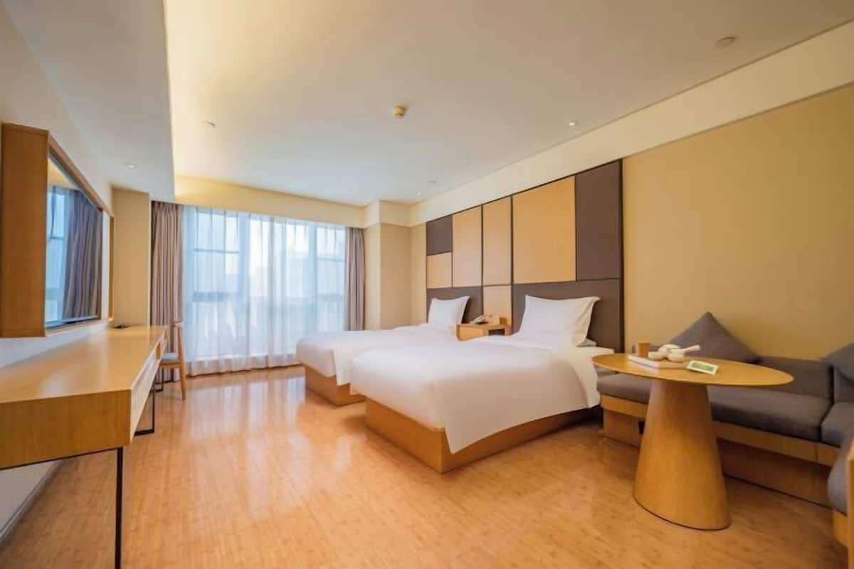 Ein Hotelzimmer mit zwei Betten, einem Schreibtisch, einem runden Couchtisch und einem Sofa.