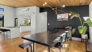 Una cocina moderna con una isla grande, taburetes de bar y una lámpara colgante.