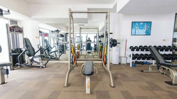 Une salle de sport équipée d’un support à squats, de bancs et d’haltères.