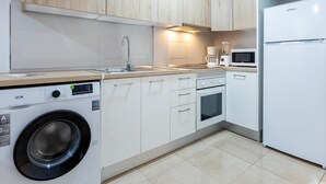 Eine moderne Küche mit weißen Schränken, einer eingebauten Waschmaschine, einer Mikrowelle und einem Kühlschrank.