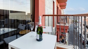 Ein Balkon mit Tisch, einer Champagnerflasche und zwei Gläsern.