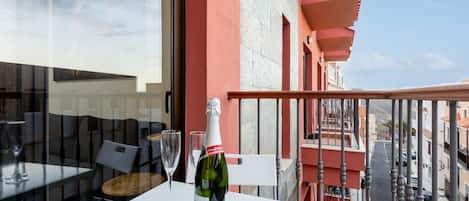 Un balcon avec une table, une bouteille de champagne et deux verres.