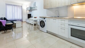 Eine moderne Küche mit weißen Schränken, einer integrierten Waschmaschine und einem Essbereich mit Tisch und Stühlen.