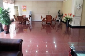 A lobby with a polished floor, seating area with chairs, and potted plants. - Jinqiao Hotel (Anji)