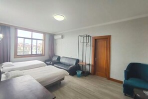 Ein Hotelzimmer mit zwei Betten, einem Schreibtisch, einem Stuhl, einem Fenster mit Aussicht und einer Tür.